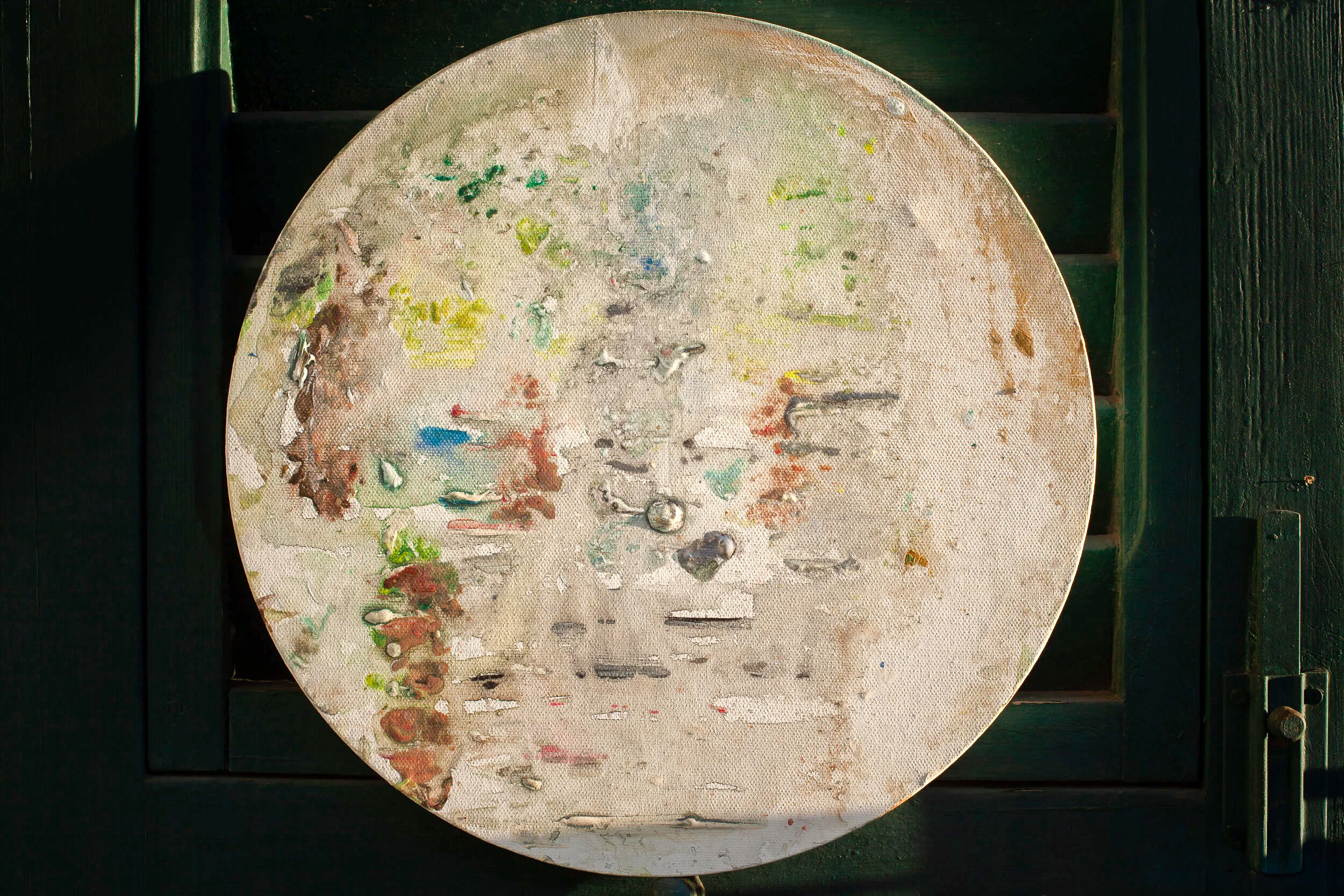 Circular canvas painting displayed on green wooden door