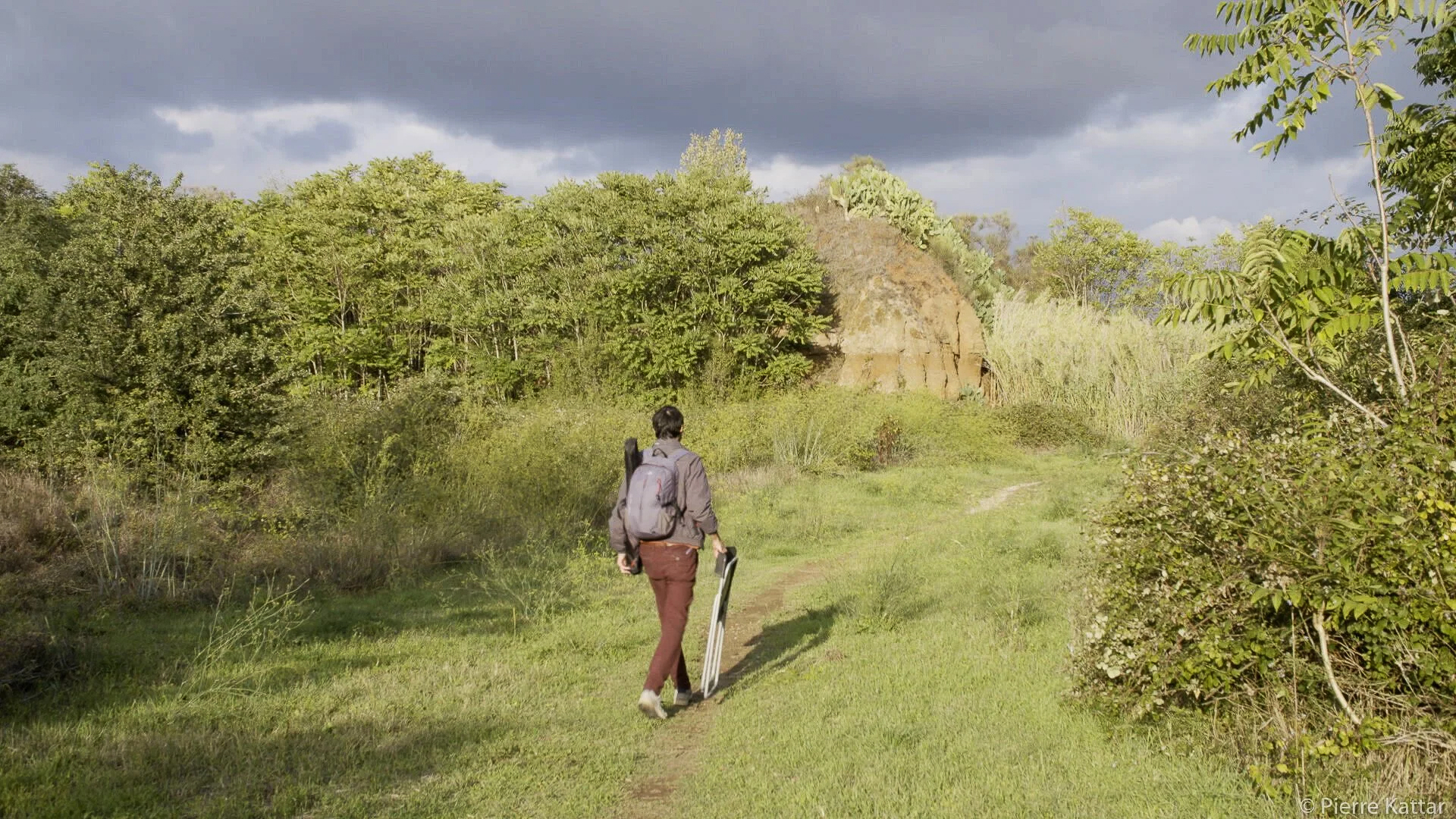 Artist walking through Tor Marancia landscape with canvases under stormy skies