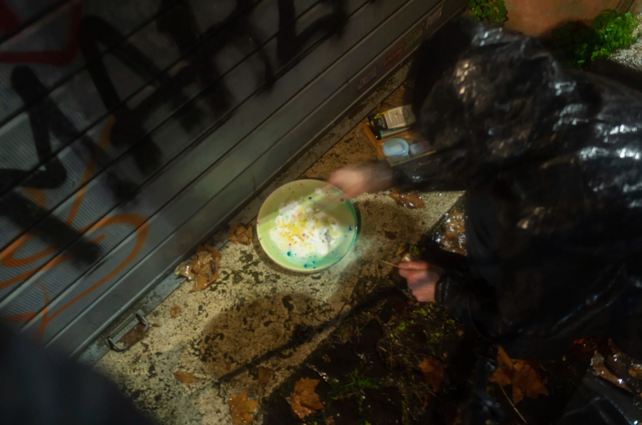 Artist painting on circular canvas by metal shutters in the rain